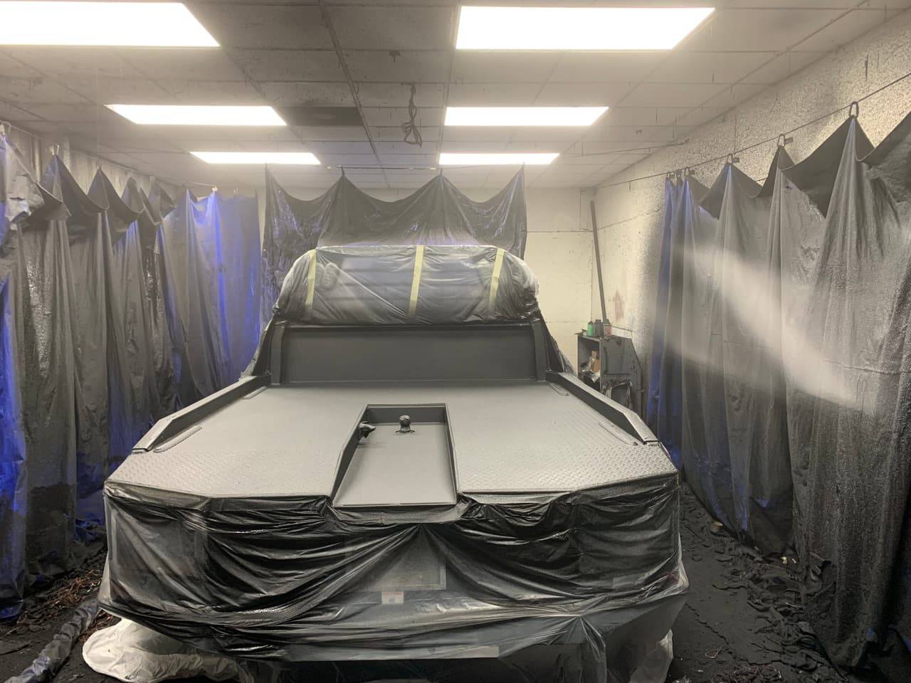 Truck bed being sprayed with bed liner during installation