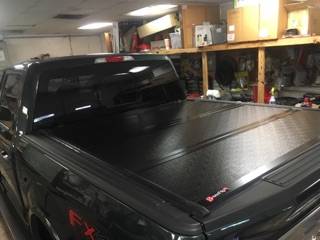 Black diamond-plate hard tonneau cover installed on a truck bed