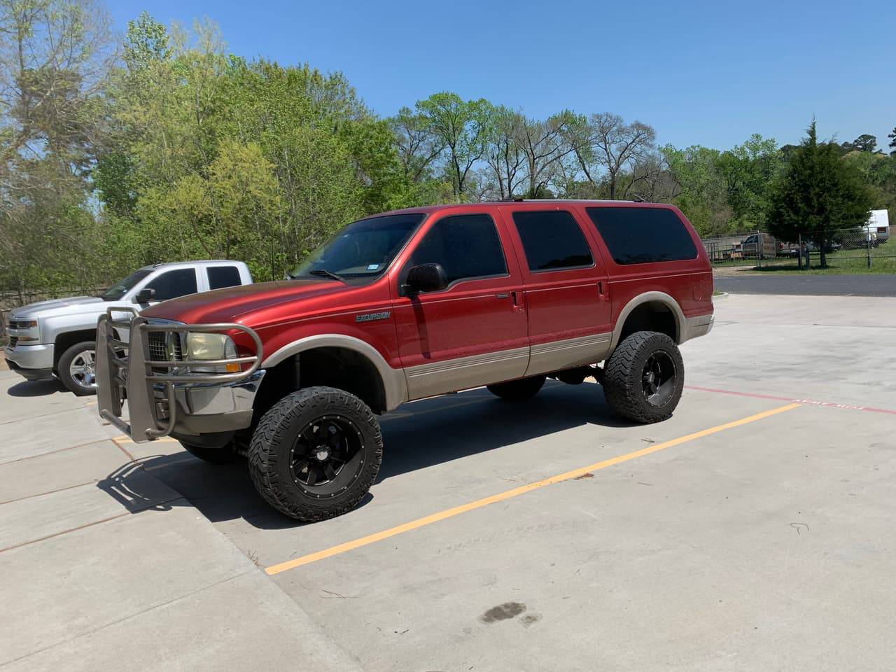Lifted red Ford Excursion with tinted side windows outside Performance Tinters II